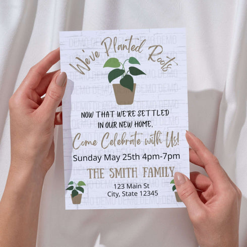 Hand holding a white invitation card with green plant illustrations and text.